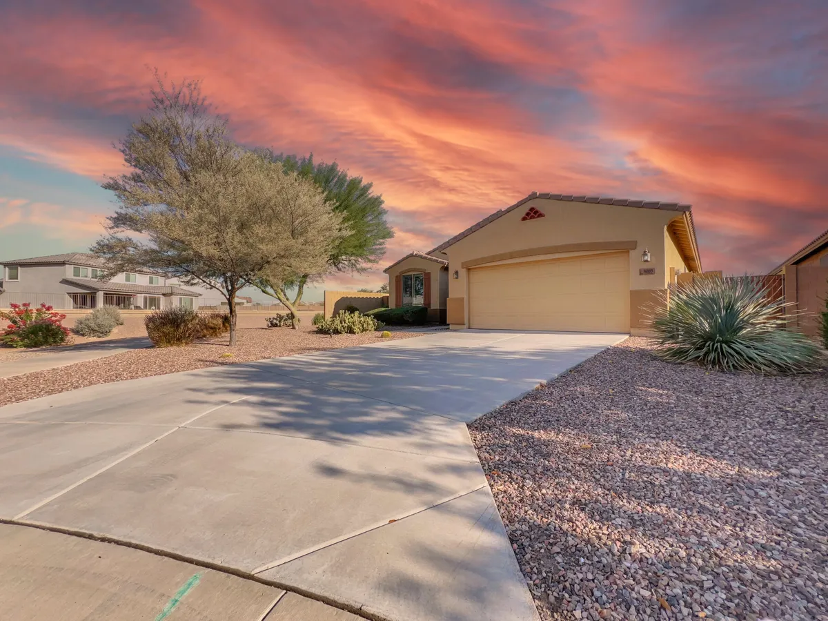 A wide view of the home exterior, featuring the house and driveway set against a colorful sunset sky. The inviting scene hints at peaceful evenings and outdoor gatherings, with a welcoming garden and ample space for activities.