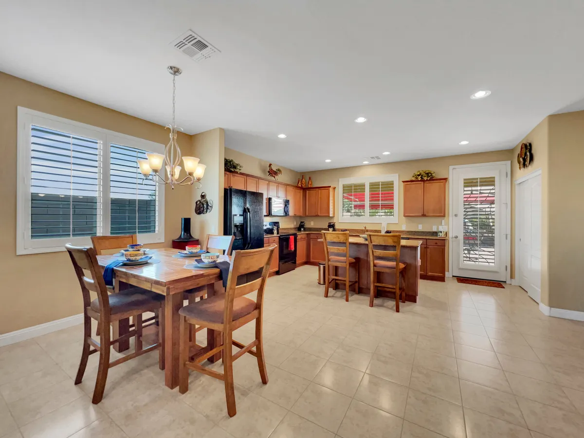 A bright view of the dining area connected to the kitchen, featuring a dining table, kitchen island, ample windows, and modern appliances. The setting is ideal for hosting meals and socializing, with plenty of sunlight streaming in.