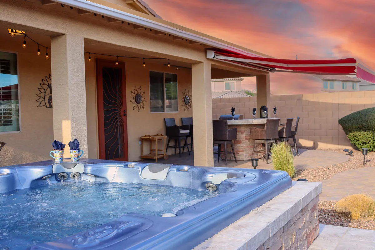 This exterior shot highlights the hot tub adjacent to a stylish outdoor dining area. Decorative wall art and soft lighting suggest a warm atmosphere ideal for evening gatherings, alfresco dining, or simply relaxing after a day exploring nearby trails. The arrangement of furniture invites guests to unwind and socialize.