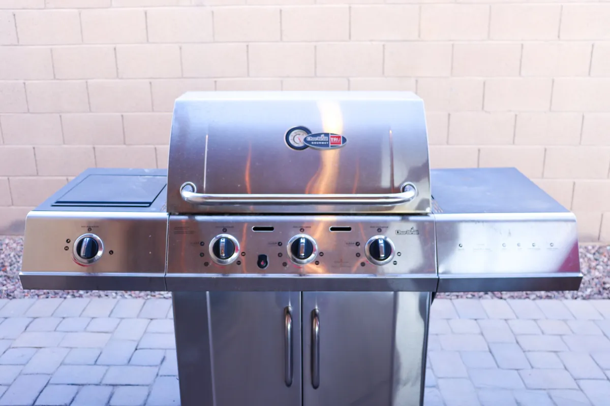 A close-up of a stainless steel barbecue grill, complete with control knobs and a side burner, set in an outdoor environment. The image captures the anticipation of grilling and sharing meals in the fresh desert air, emphasizing the culinary experiences available in the backyard space.
